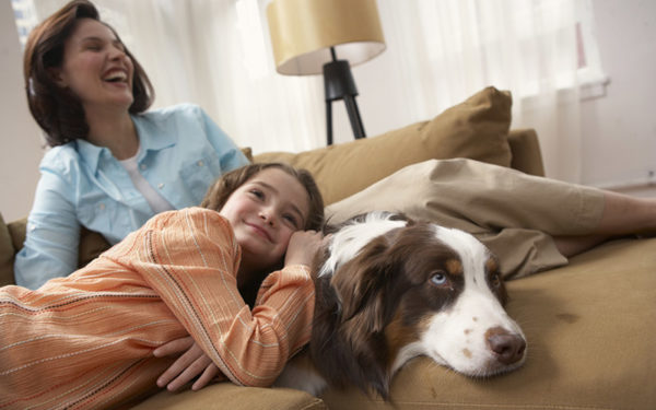 Mother and daughter relaxing on couch with dog